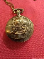 Front view of pocket watch showing embossed steam locomotive train design on cover
