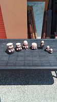 All 7 monk figurines arranged on a surface outdoors, showing varying sizes.