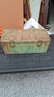 Side view of rusted WWII metal box with green paint.
