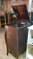Full view of wooden phonograph cabinet with hinged lid open, revealing turntable.
