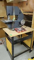 Front view of Sears Craftsman band saw mounted on a metal stand with wooden top showing blade and table surface.