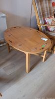 Oval wooden table with removable tray top placed on floor next to furniture.