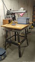 Full view of radial arm saw mounted on metal stand with plywood top