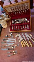 Full view of William Rogers flatware set on table showing knives with ivory handles, various forks and spoons, and wooden storage case with lid open