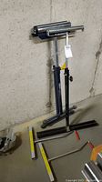 Photo showing the helping hand roller standing upright against a concrete wall with panel carriers placed horizontally on floor nearby.