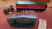 Photo shows the Eaton toy 18 wheeler truck and the Inuit stone carving placed side by side on a carpeted floor.