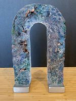 Front view of U-shaped clear glass sculpture with colored textured surface and aluminum bases