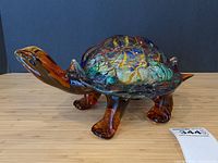 Full side view of multicolored glass turtle figurine facing left on wooden surface