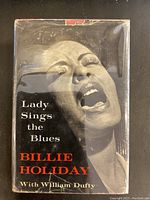 Front cover of dust jacket showing title, author credit and Billie Holiday portrait, with visible edge scuffs and tears.