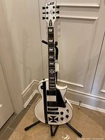 Full view of white guitar on stand