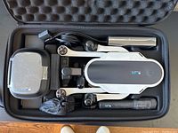 Overview of Karma Drone kit inside foam case showing folded drone body, gimbal grip, battery and cables