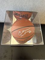Top-down view of signed basketball inside clear acrylic case showing signature placement and mirrored base