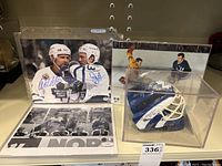 Color and black-and-white photos alongside mini helmet in acrylic case