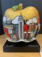 Front view showing golden apple shape with Empire State Building relief and rhinestones