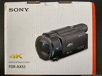 Front of sealed white-and-orange Sony box showing model name FDR-AX53, 4K and Handycam branding