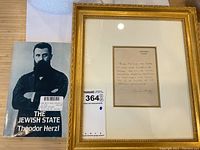 Main view showing framed letter and paperback book side by side