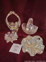 Four unique hand blown glass baskets arranged on burgundy velvet background
