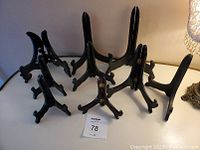 Nine black stands arranged in a group on a white surface showing variety in size and shape.