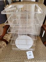 Front and side view of the acrylic multi-tier display case placed on patterned chair, showing tiered compartments.