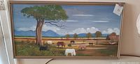 Full view of rectangular folk art pastoral landscape painting depicting cattle with tree and barn in rural scene, framed.