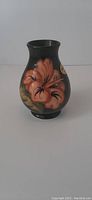 Front view showing peach hibiscus on green background on Moorcroft vase.
