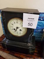 Front and angled view of slate and marble mantle clock showing dial, wear and slate chip on the corner