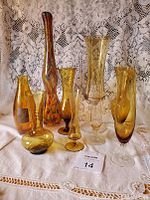 Photo showing the full group of 9 amber hand blown glass vases, varying in shape and size, some with textured or wavy glass, one multicolored vase.