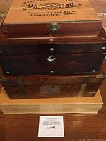 Four wooden boxes stacked; top box labeled 'Handmade in Honduras, Imported Long Filler Connecticut Select' with latch; others are darker wood with metal accents and keyholes