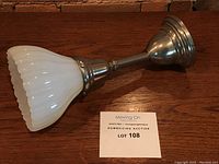 Antique ceiling light resting on wood surface showing metal base and white glass shade