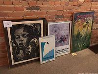 All four framed prints and posters leaning against brick wall
