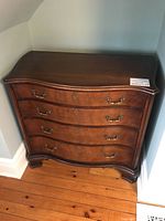 Front view of serpentine chest of drawers with four drawers and brass bail handles