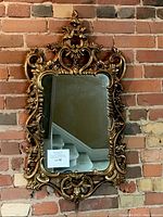 Full front view of ornate French style giltwood mirror with carved scrolling and floral details.