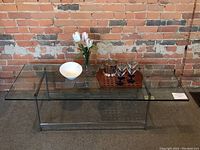 Full view of rectangular mid century modern coffee table with clear glass top on chrome base, showing overall design and condition.