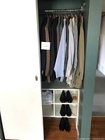 Closet with men's dress blazers and jackets, several pairs of dress shoes at bottom