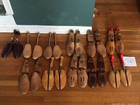 Overview of all 11 pairs of men's shoe trees showing variety of wood finishes and styles including vented and suspenders.