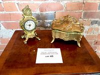 Clock and jewellery box displayed on wood table against brick wall