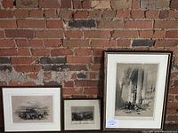Three framed etchings by David Roberts arranged against a brick wall, showing their relative sizes and framing.