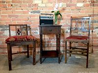 View of side table, two vintage chairs, and Sanyo radio on side table against brick wall background