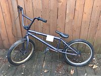 Full side view of BMX bike showing charcoal frame, 20-inch tires, and handlebar style.
