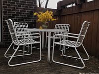 Wide shot showing four chairs arranged around round glass-top table on deck.