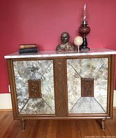 Front elevation of cabinet showing wooden frame, two doors with textured glass panels, carved wood appliques, marble top