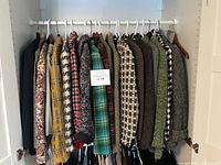 First row of blazers on white plastic and wooden hangers showing plaids and tweeds