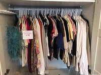 Full view of hanging women's small and extra small tops and sweaters in various colors.