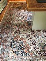 Overall view of rug under coffee table and armchair on hardwood floor showing pattern and scale