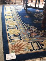 Corner of rug showing navy field, cream border with floral motif and lot card marked “10' x 8'”