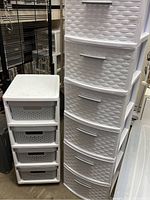 Two white plastic drawer organizers placed side by side: a 4-drawer unit with perforated drawers on casters and a 6-drawer unit with basket-patterned drawers without wheels.