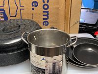 Overview photo showing stack of three frying pans, stainless steel stock pot, and black crock pot with lid.