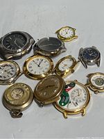 Overview of all watch faces showing gold and silver tones, some with visible internal parts and various dial designs.