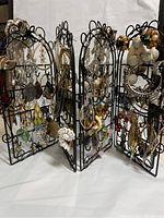 Full view of the black metal earring holder fully adorned with various pairs of earrings.