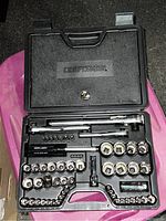 Open black plastic Craftsman tool case showing organized chrome tools including sockets, ratchets, and accessories